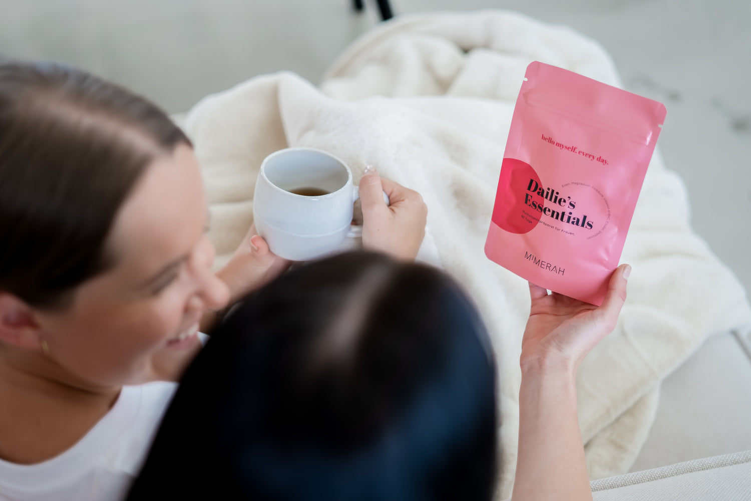 zwei freundinnen sitzen zusammen, reden und schauen sich produkt dailies essentials an