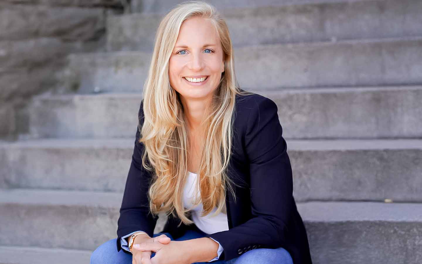 dr. eva buchkremer gründerin von mimerah sitzt auf einer treppe und schaut direkt in die kamera