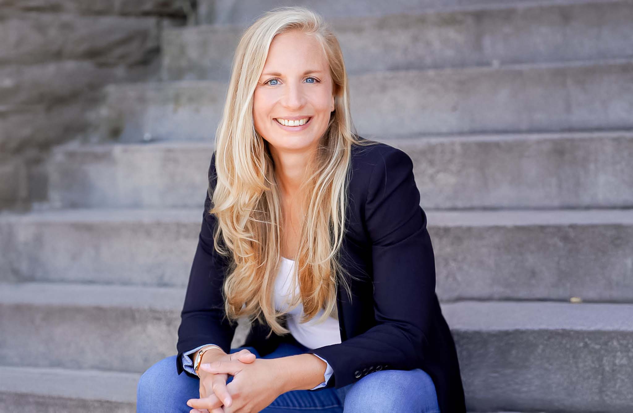 gründerin dr. eva buchkremer sitzt auf einer treppe und schaut direkt in die Kamera