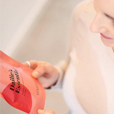 kollektionsbild energie & immunsystem frau hält dailies essentials nahrungsergänzungsmittel in der hand